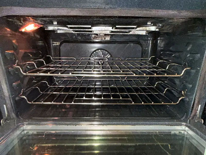 The same oven interior after a move-out clean, with racks and walls wiped clean